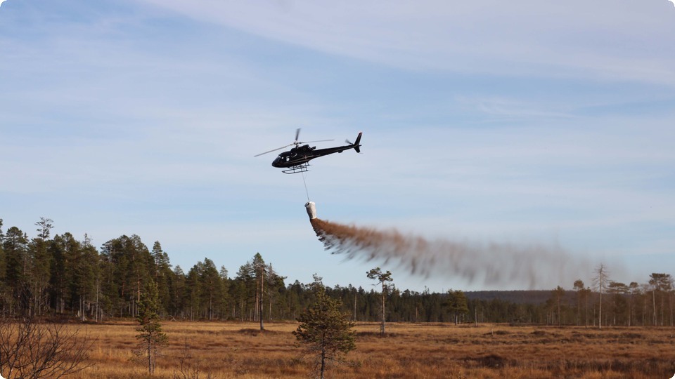 Helikopter sprider kalk över träsk.