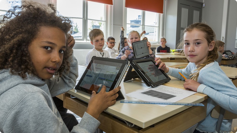 Barn i ett klassrum som visar upp sina iPads