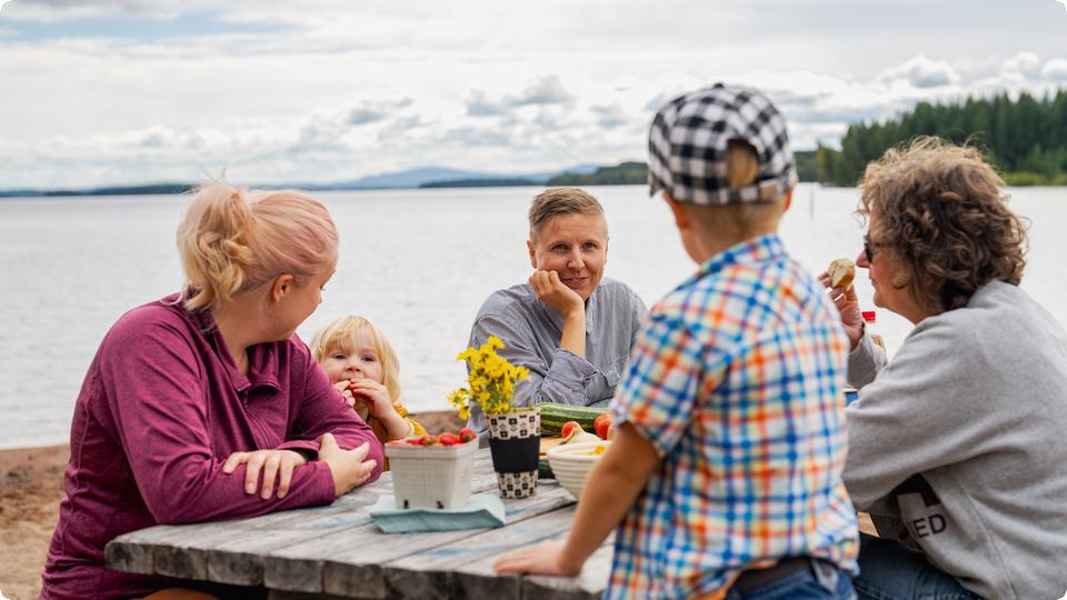 Familj som har picknick på vid sjö.