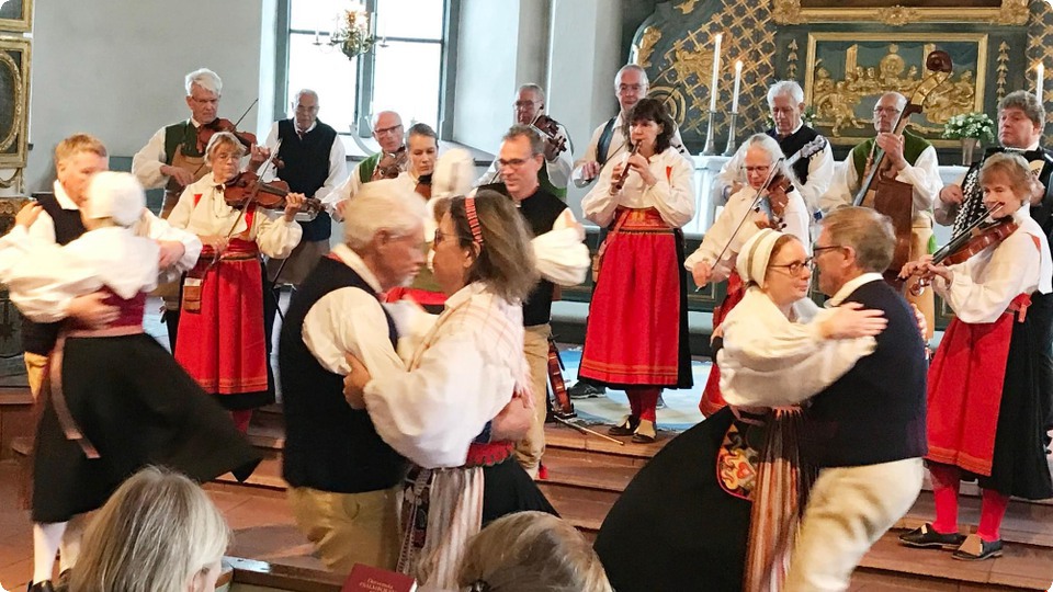 Spelmanslag spelar och dansar i kyrka.