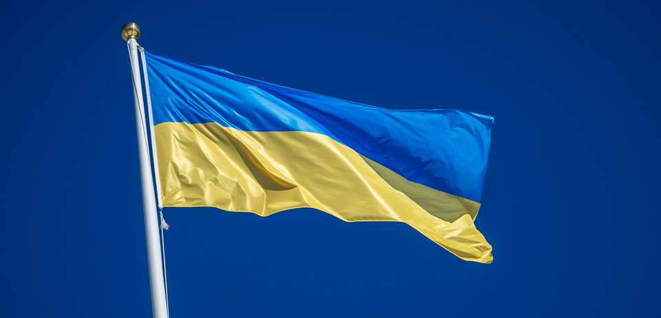 Ett foto på en hissad Ukraina-flagga mot en blå himmel.
