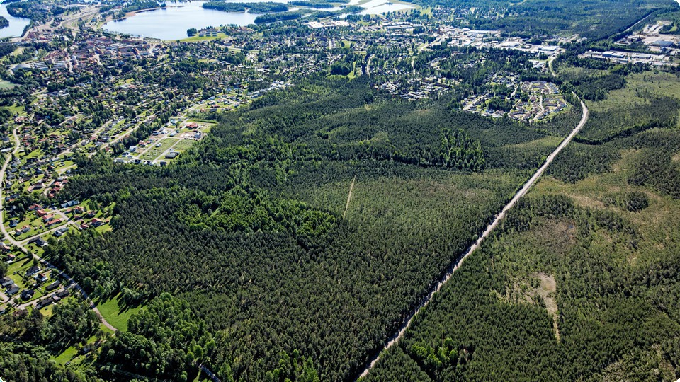Flygbild över skogsområde i utkant av tätort.