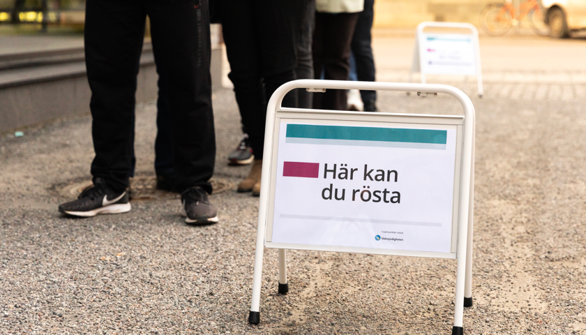 En grupp människor som står på led bredvid en skylt.