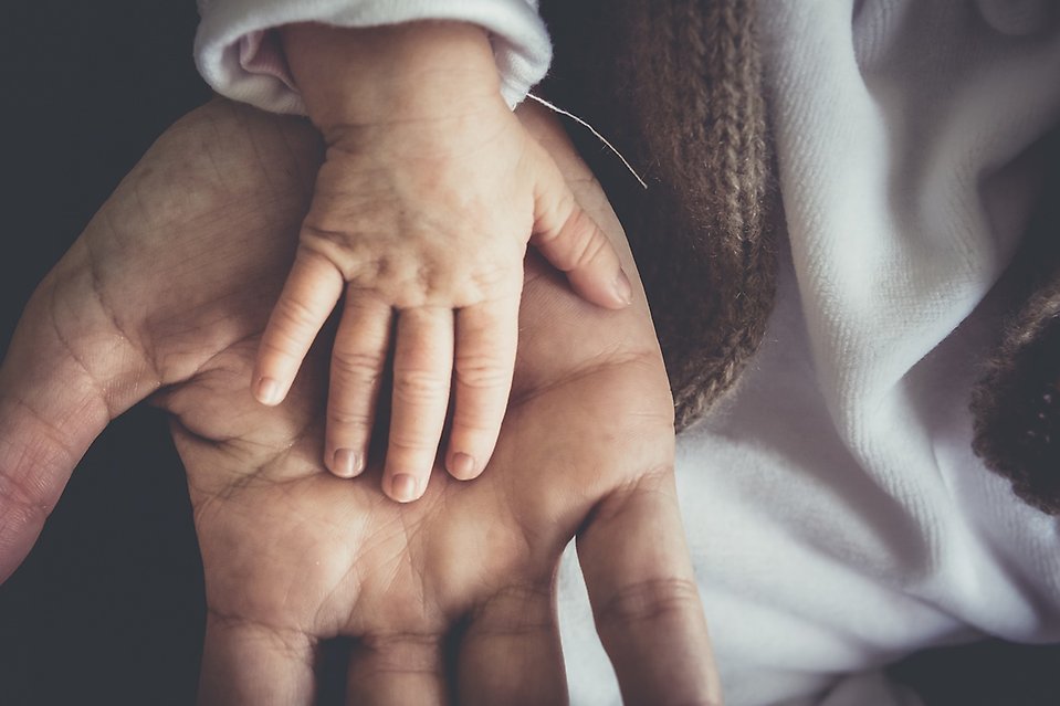 Ett barns hand ligger i handflatan på en vuxen persons hand