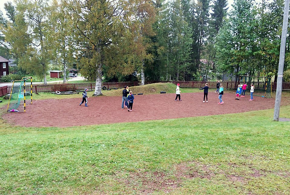 Grusplan med fotbollsmål och barn som spelar boll