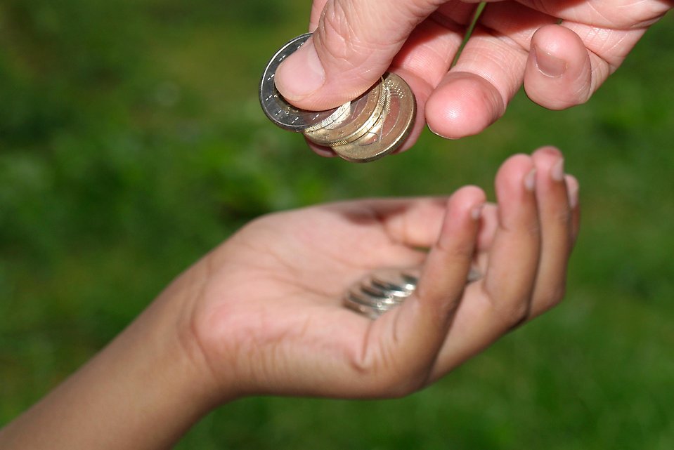 Mynt som delas ut från en hand till en annan hand