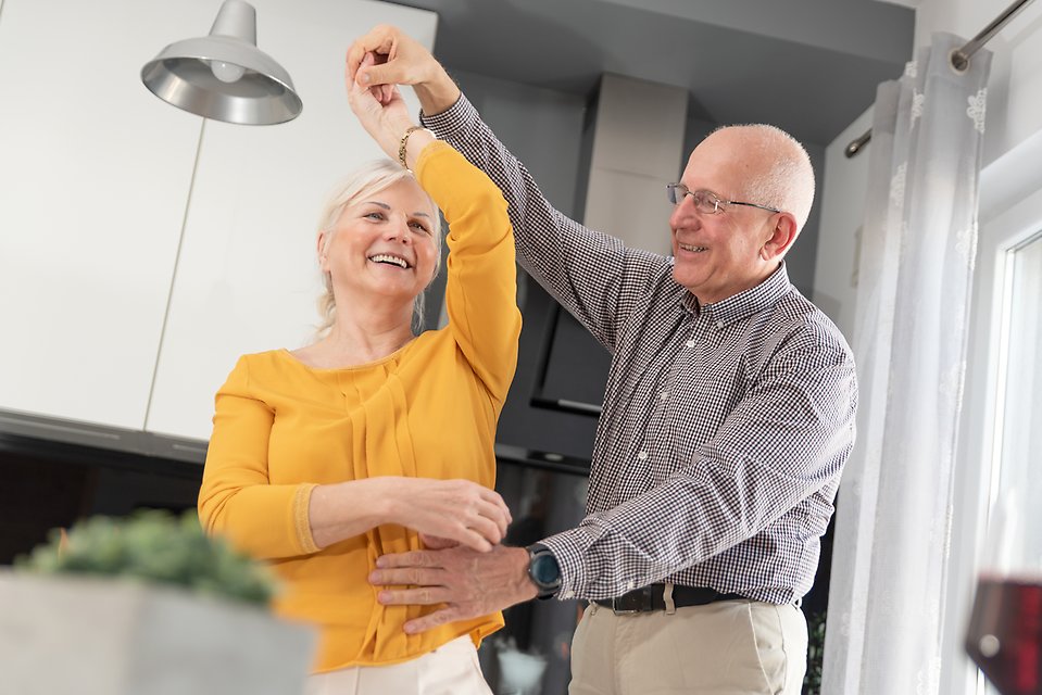 äldre par dansar och ler hemma