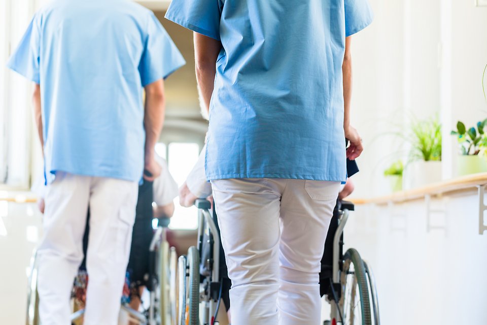 Två sköterskor rullar på patienter i rullstol