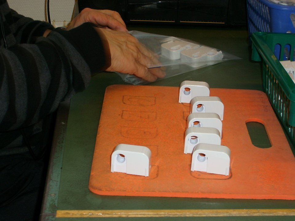 En person placerar små plastdelar på en bänk