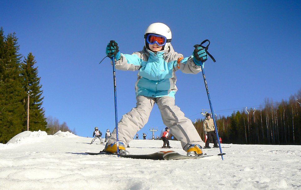 Barn på slalomskidor som plogar sig nerför en backe.