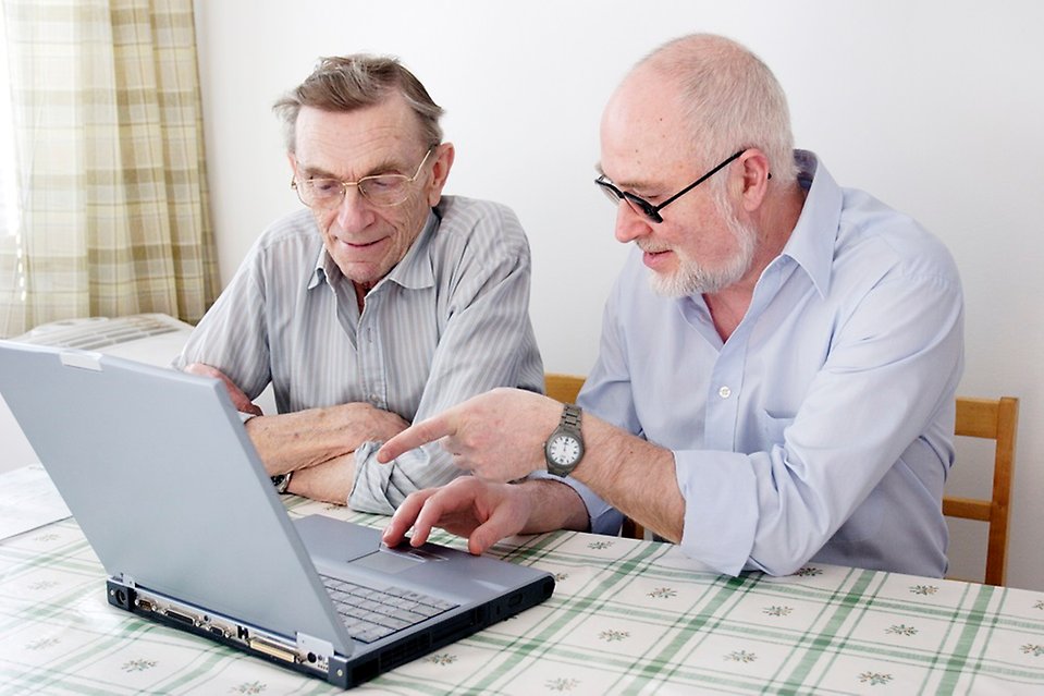 Foto på två äldre män som sitter vid en laptop