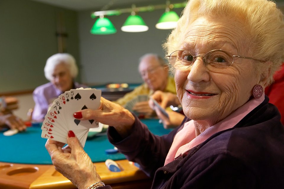 En äldre kvinna visar upp sina kort under ett bridge-spel