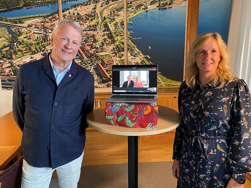 Kommundirektör Peter Karlsson och kommunstyrelsens ordförande Anna Hed (C) står vid datorn där de har ett digitalt möte med kronprinsessan Victoria och prins Daniel.