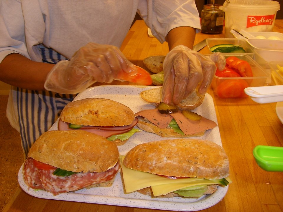 Foto på person som lägger pålägg på smörgåsar