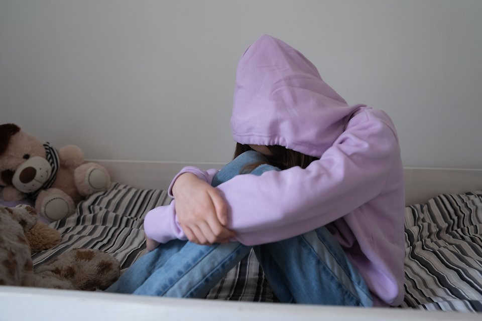 Barn som gömmer ansiktet under en huvtröja