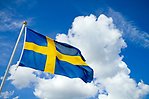 Svensk flagga mot molnig himmel.